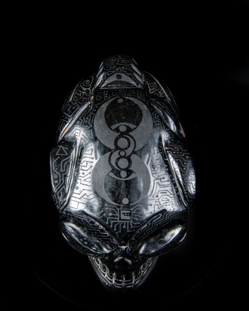 An alien head that is silver and has a lot of symbols on it